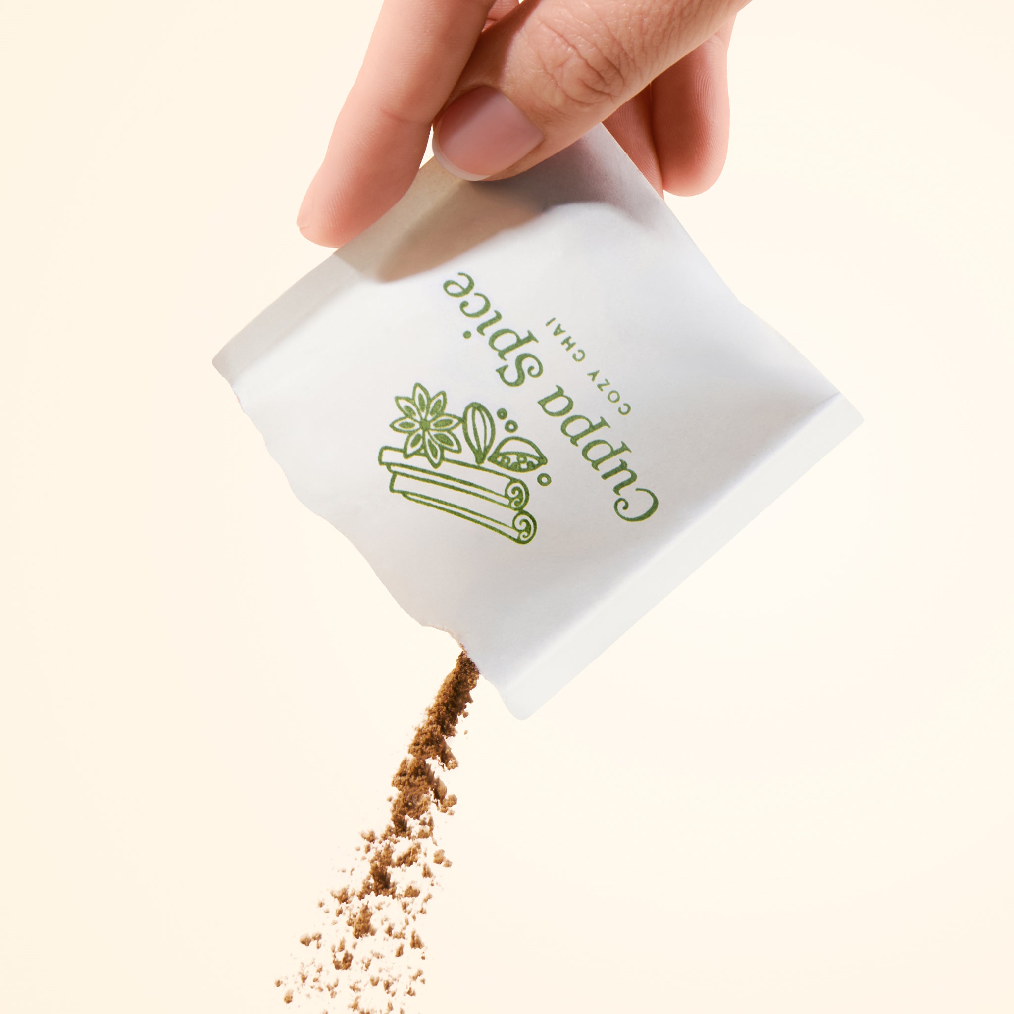 Hand holding a white packet with spices pouring out