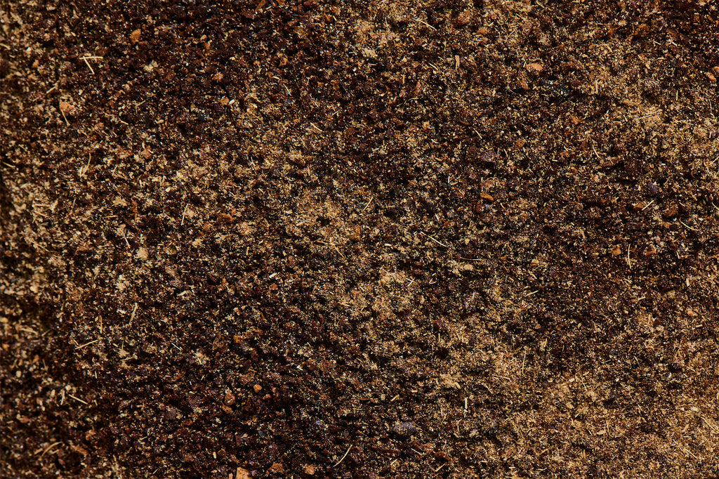 Close-up of vanilla bean powder and ground lavender on coffee grounds