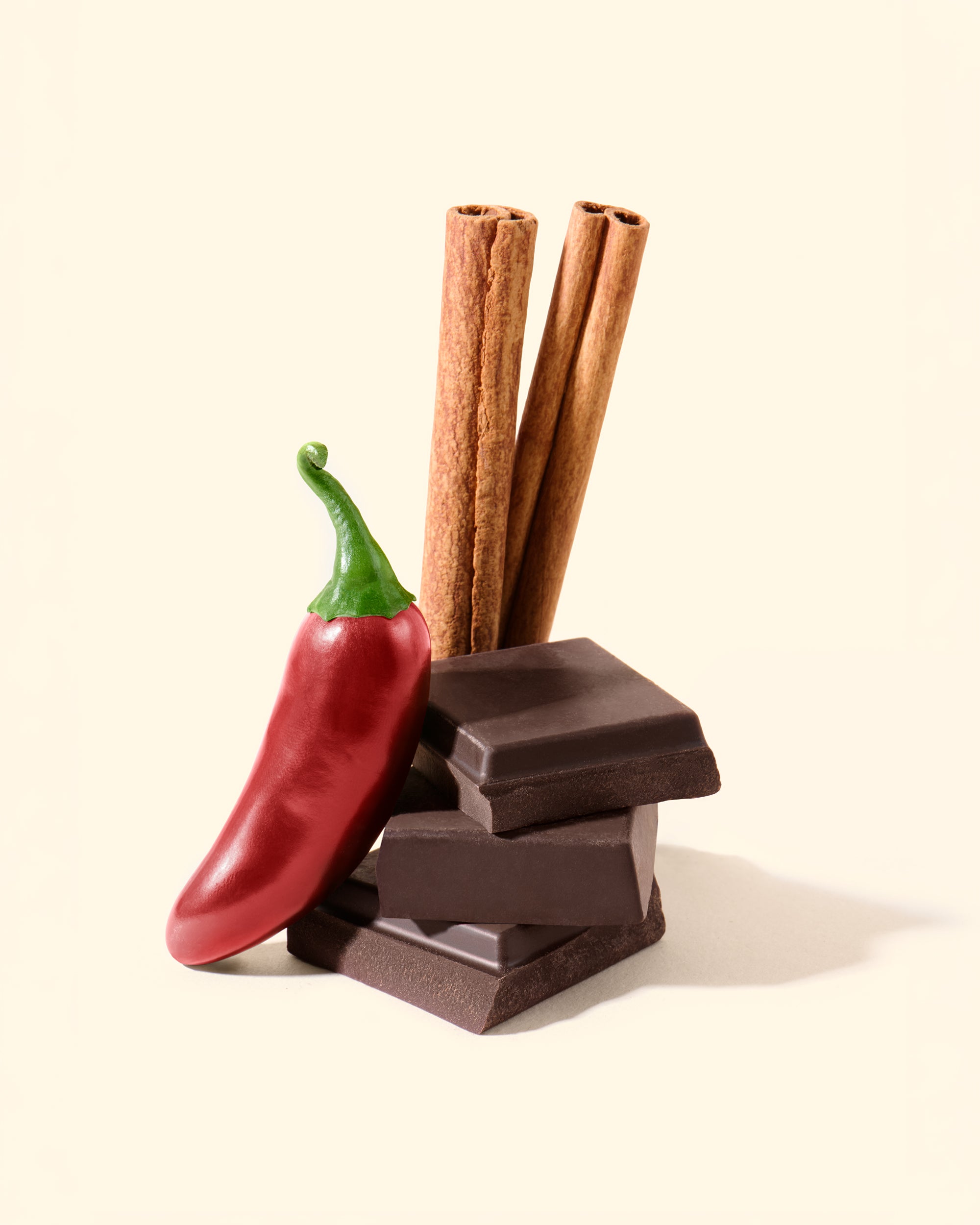 Chocolate bars, red chili pepper, and cinnamon sticks on a beige background